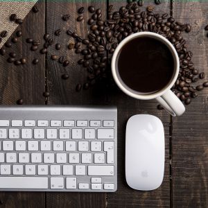Caneca de Café, grãos de café, um teclado e mouse